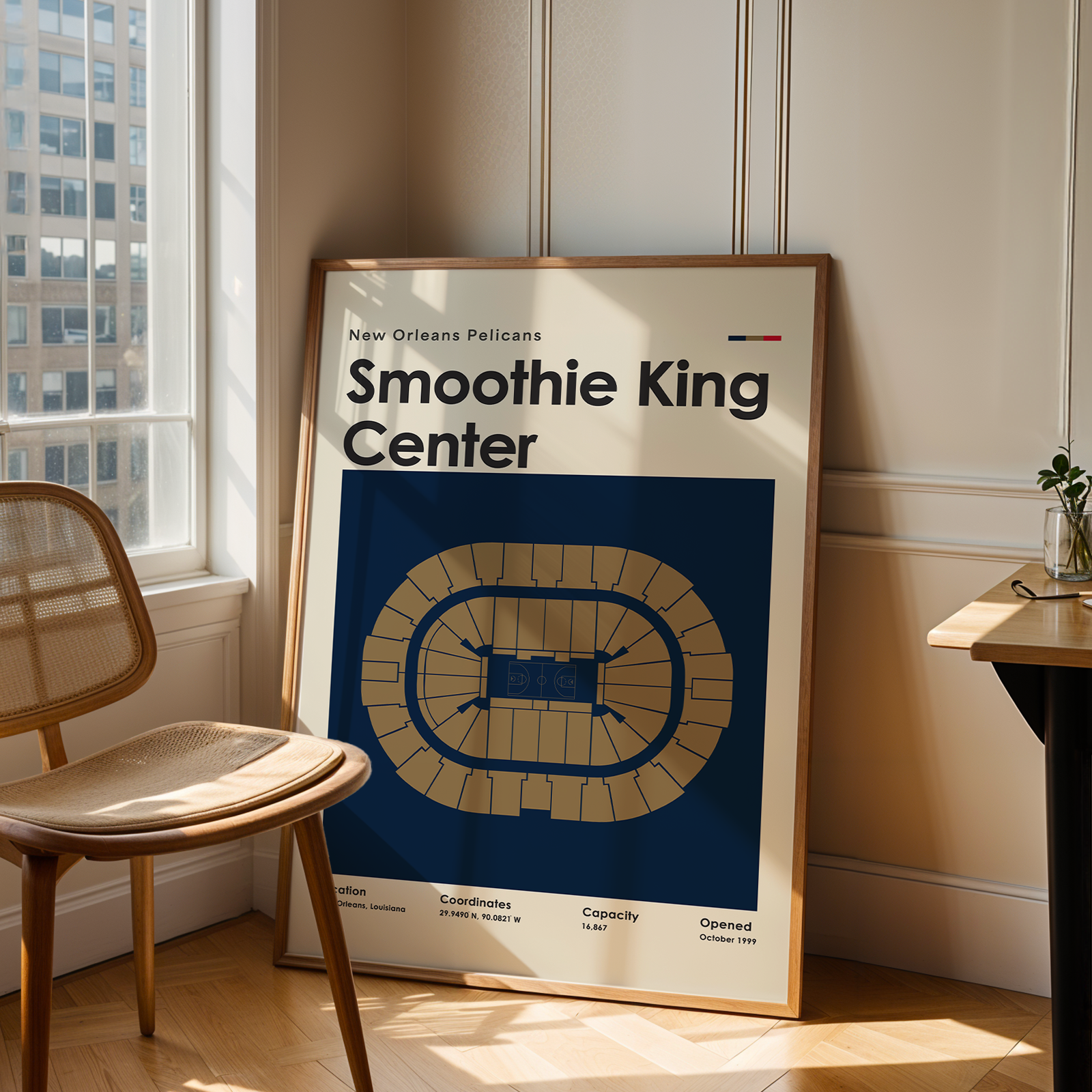 Framed poster of Smoothie King Center in a room with a chair and table.