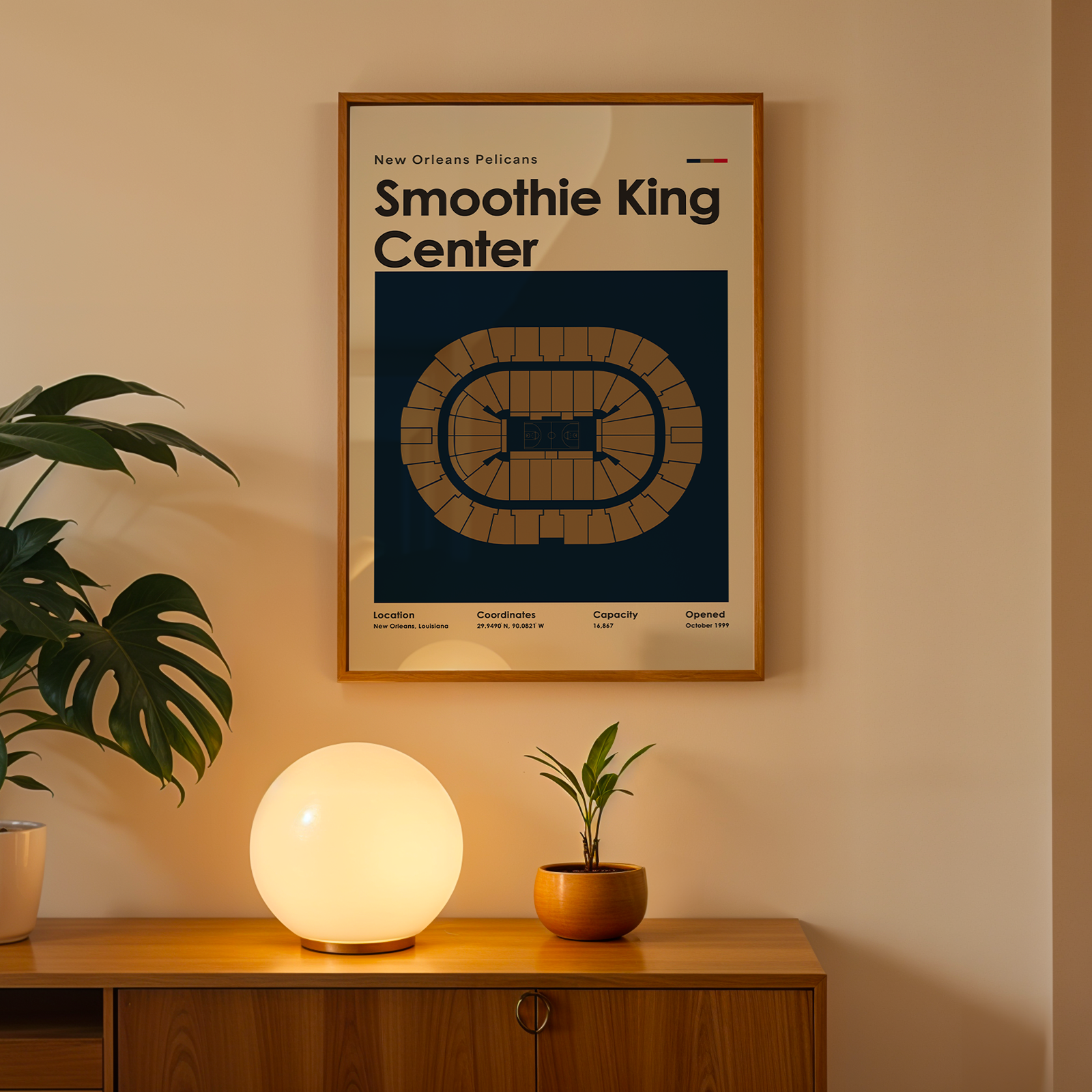 Framed poster of Smoothie King Center on a wall above a wooden cabinet with decorative items.