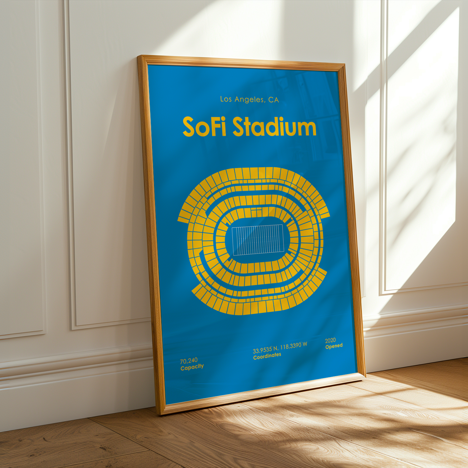 Framed poster of SoFi Stadium with blue background and yellow seating pattern on a white wall.