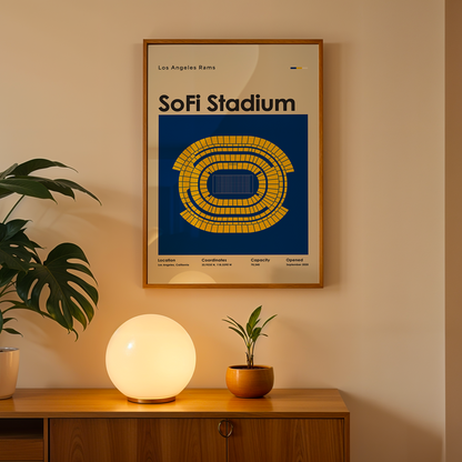 Framed poster of SoFi Stadium on a wall above a wooden cabinet with decorative items.