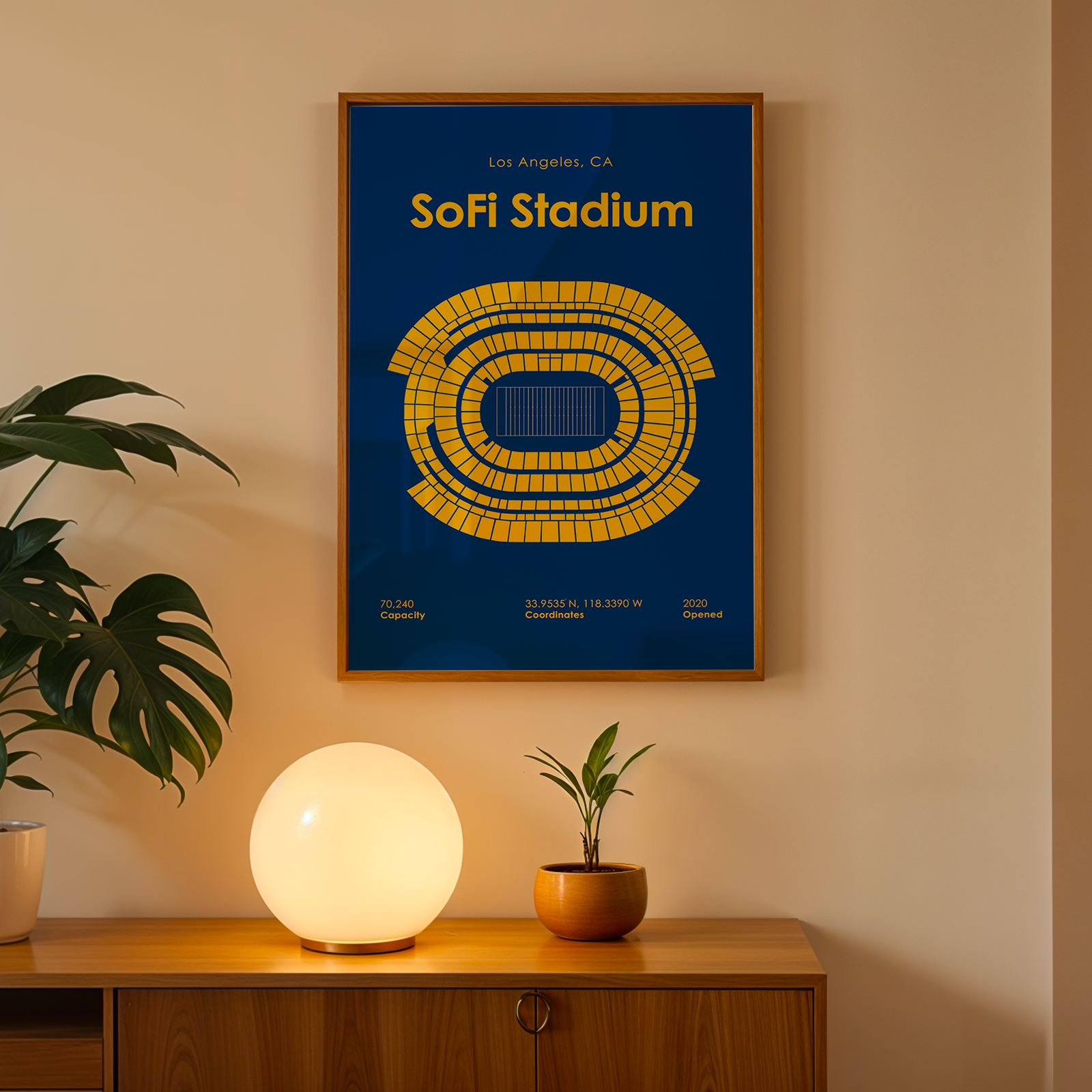 Framed poster of Sofi Stadium on a wall above a wooden cabinet with decorative items.
