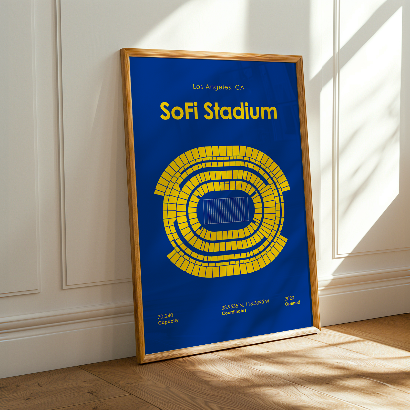 Framed poster of SoFi Stadium layout on a wall with sunlight casting shadows.