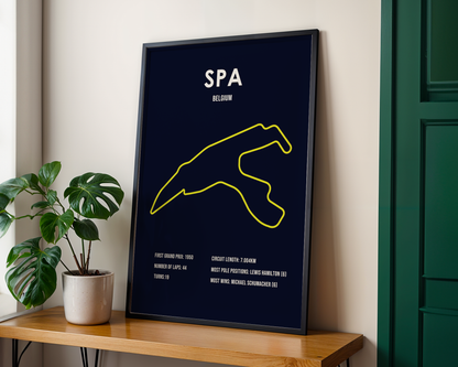 Framed poster with yellow outline of a race track on a black background, placed on a wooden shelf.