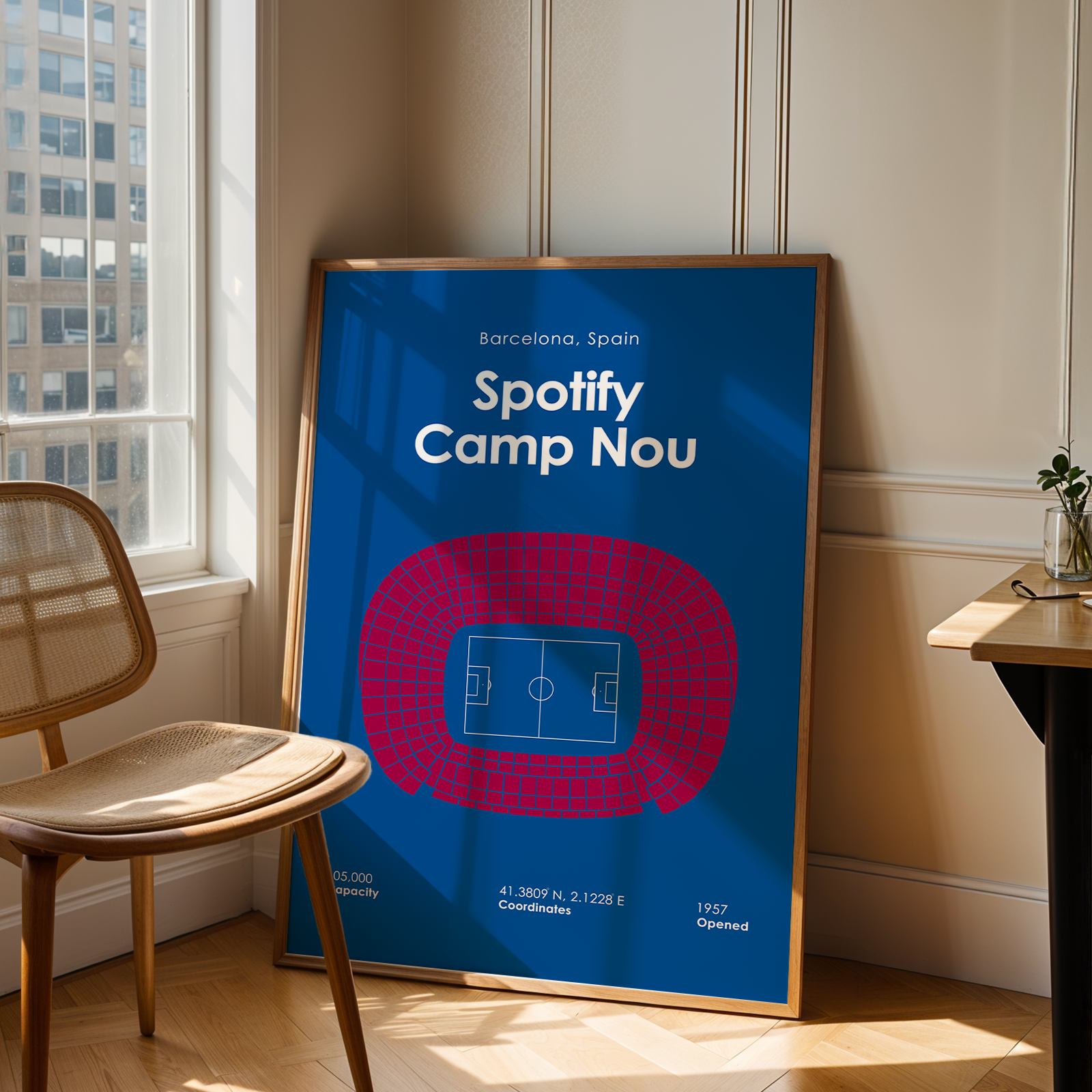 Framed poster of Spotify Camp Nou in a room with a chair and window.