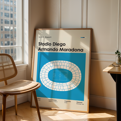 Framed poster of Stadio Diego Armando Maradona in a room with a chair and table.