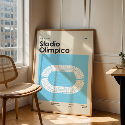 Framed poster of Stadio Olimpico in a room with a chair and table.