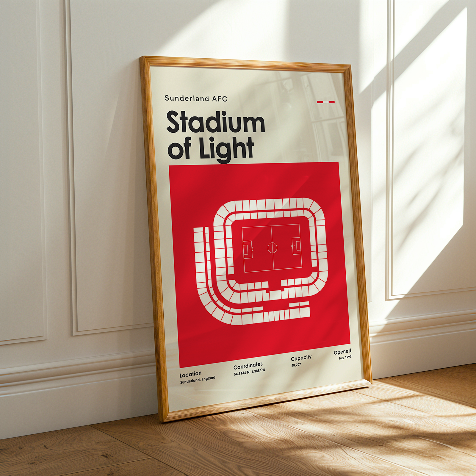 Framed poster of Sunderland AFC Stadium of Light on a wooden floor with sunlight streaming through a window.