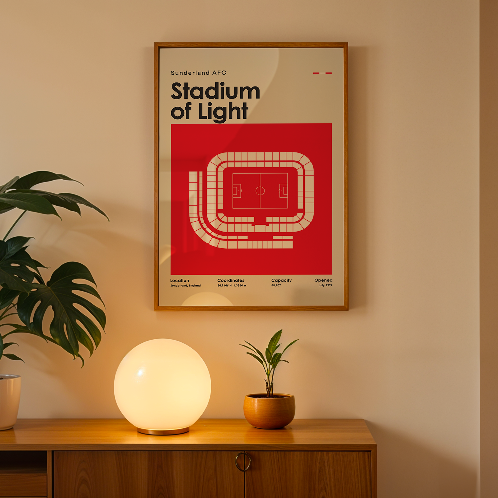 Framed poster of Sunderland AFC Stadium of Light on a wall above a wooden cabinet with decorative items.