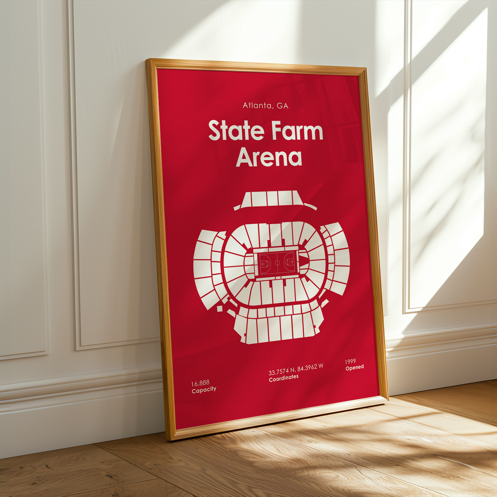 Framed poster of State Farm Arena on a red background with white text and diagram, leaning against a white wall.