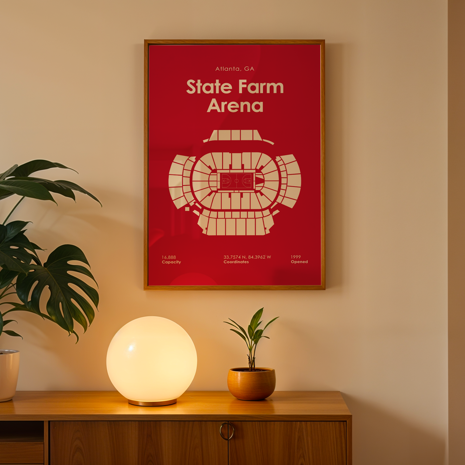 Framed poster of State Farm Arena on a wall with a lamp and plant on a wooden surface.