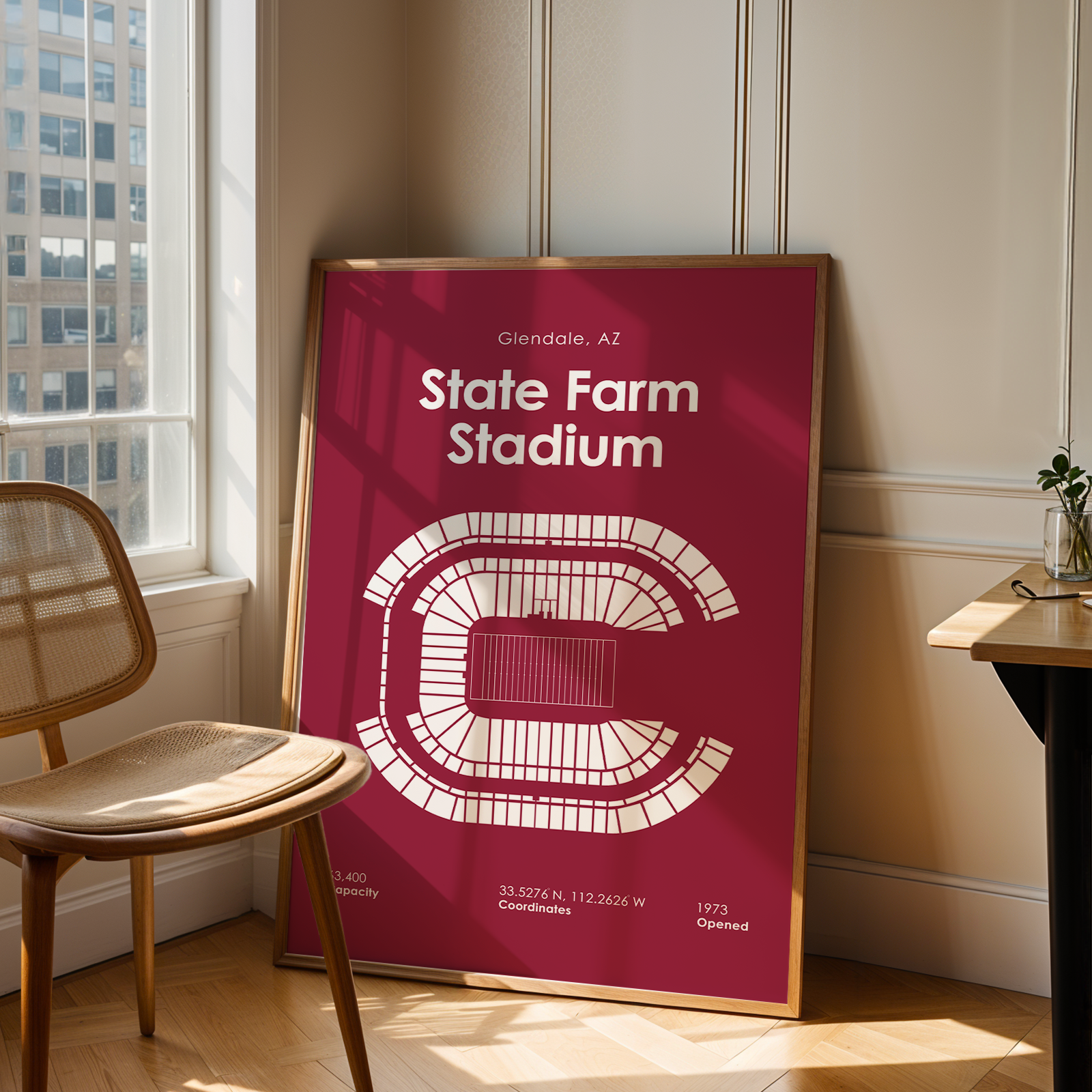 Framed poster of State Farm Stadium in a room with a chair and table.