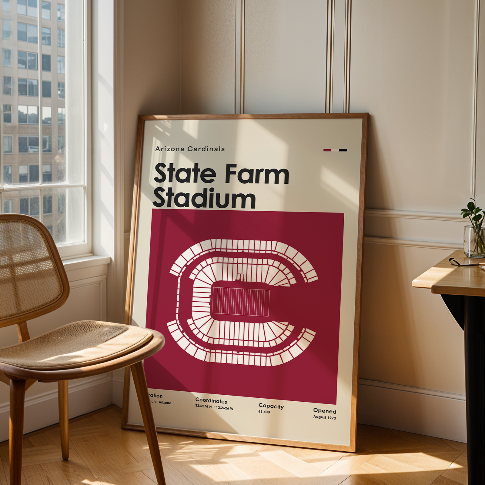 Framed poster of State Farm Stadium in a room with a chair and table.