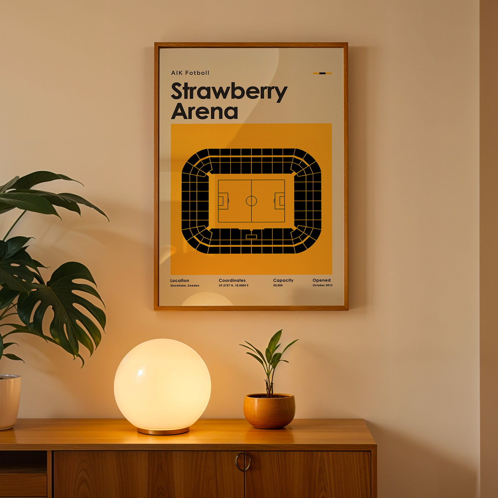 Framed poster of Strawberry Arena on a wall with a wooden cabinet and decorative items below.