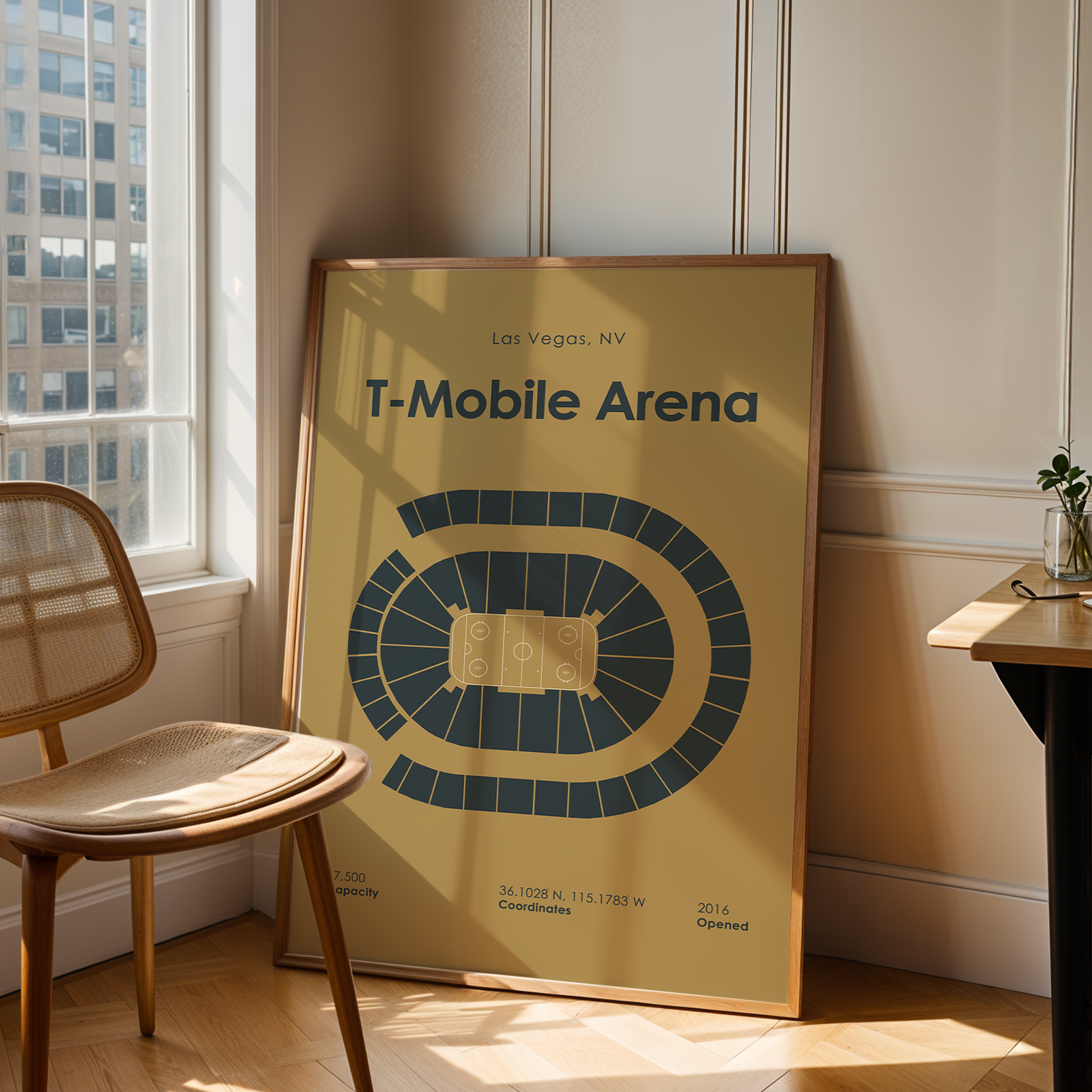 Framed poster of T-Mobile Arena in Las Vegas, NV, leaning against a wall in a room with a chair and window.