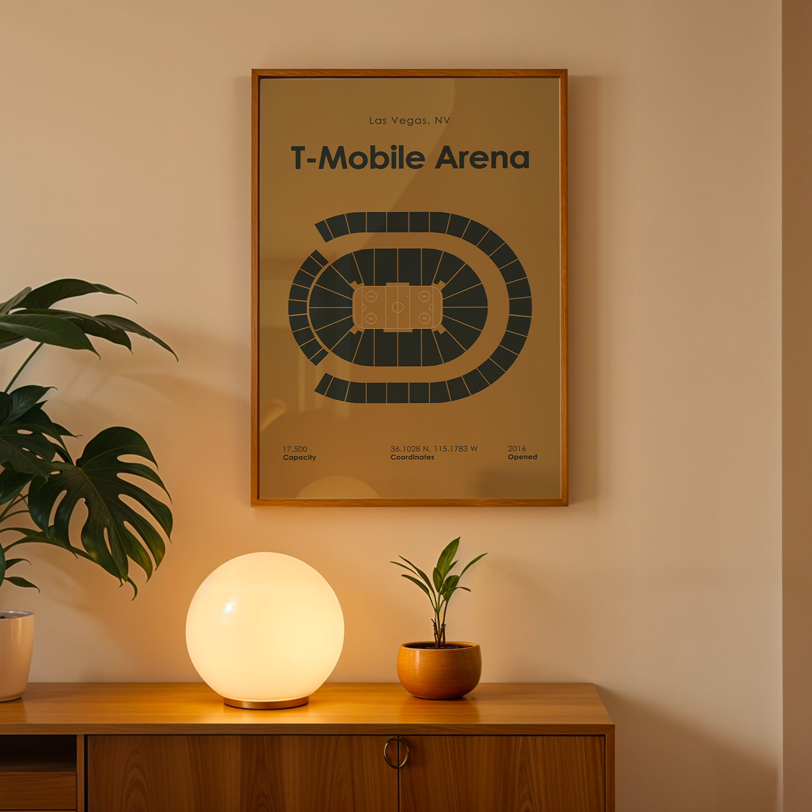 Framed poster of T-Mobile Arena on a wall above a wooden cabinet with a lamp and plant.