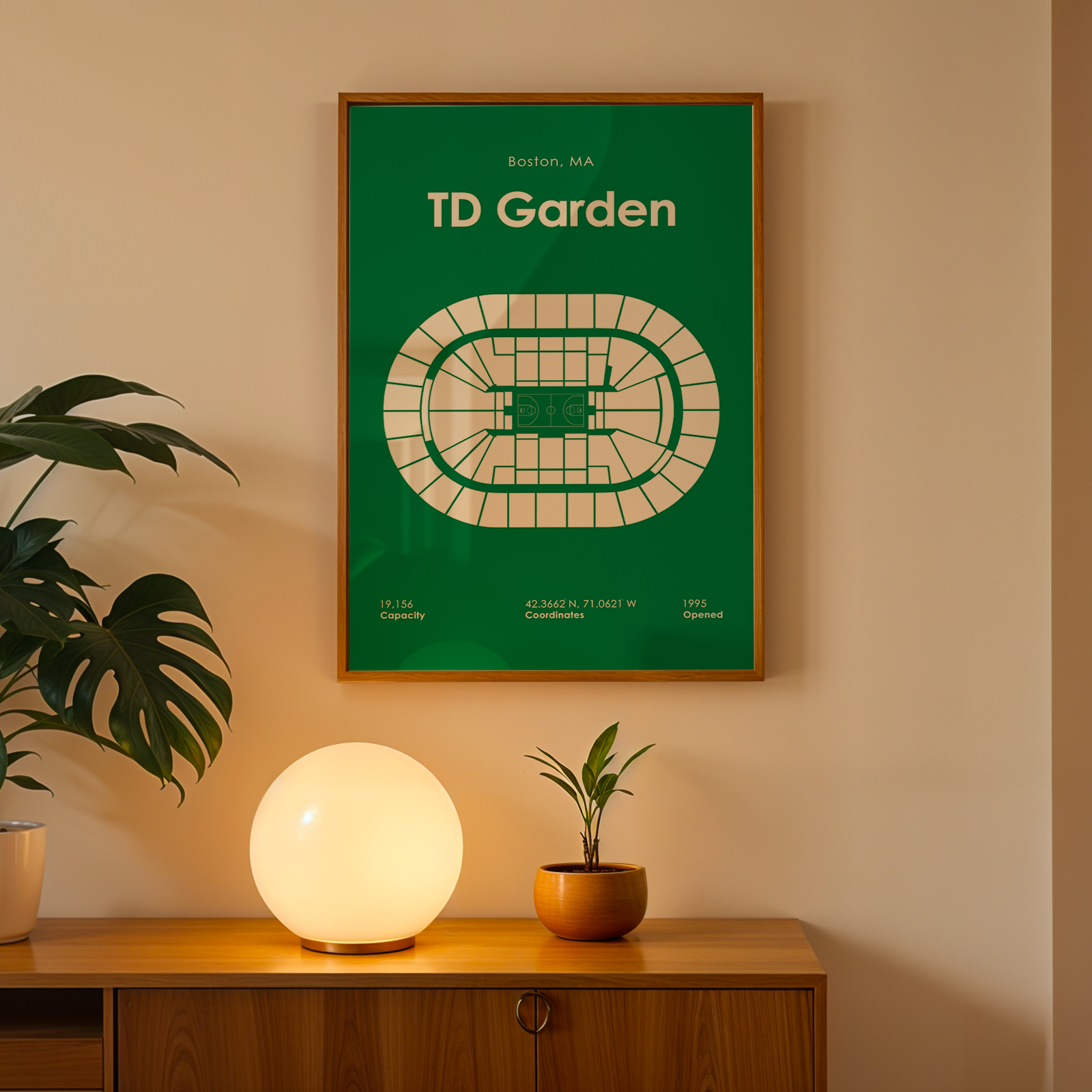 Framed poster of TD Garden on a wall with a lamp and plant below.