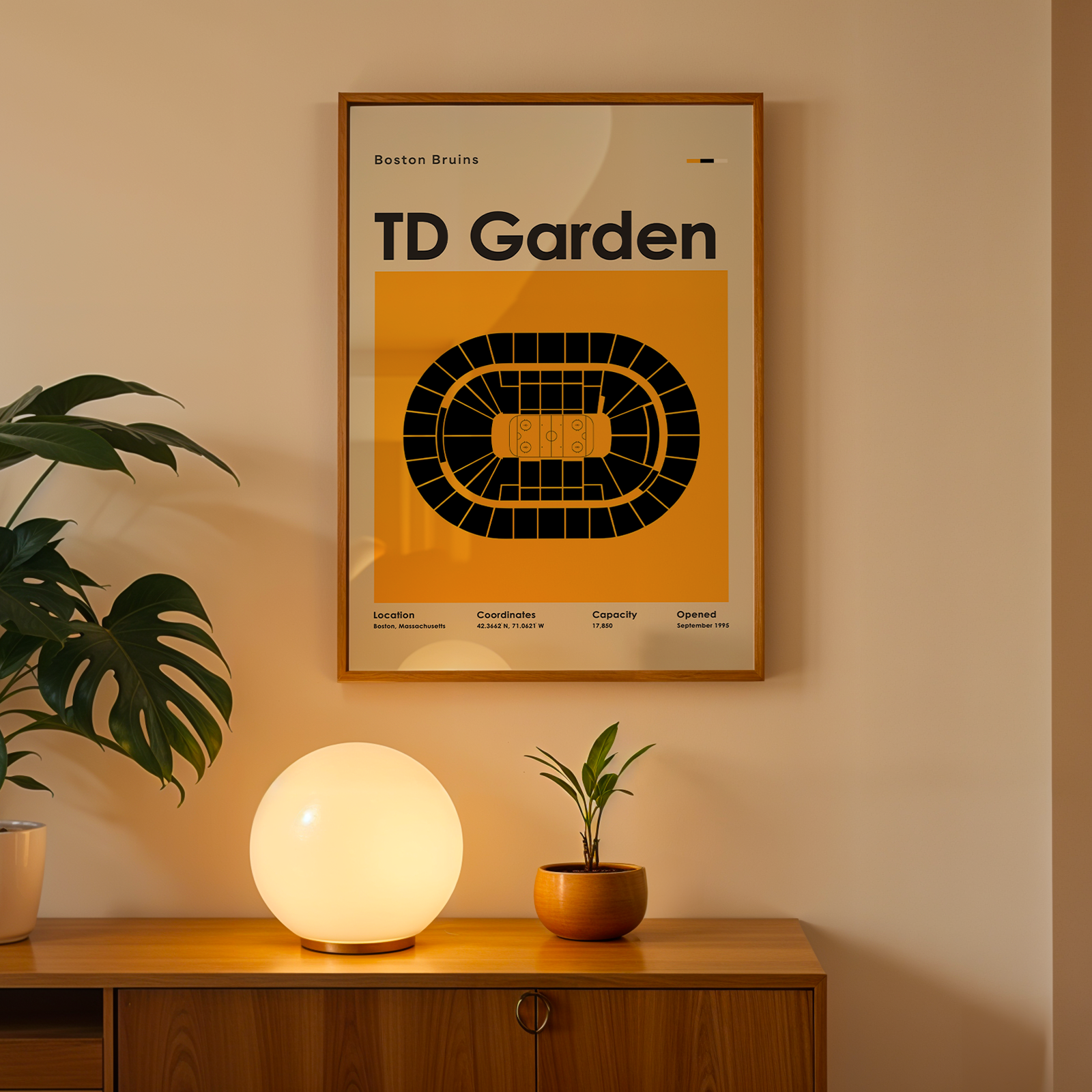 Framed TD Garden poster on a wall with a plant and lamp on a wooden surface below.