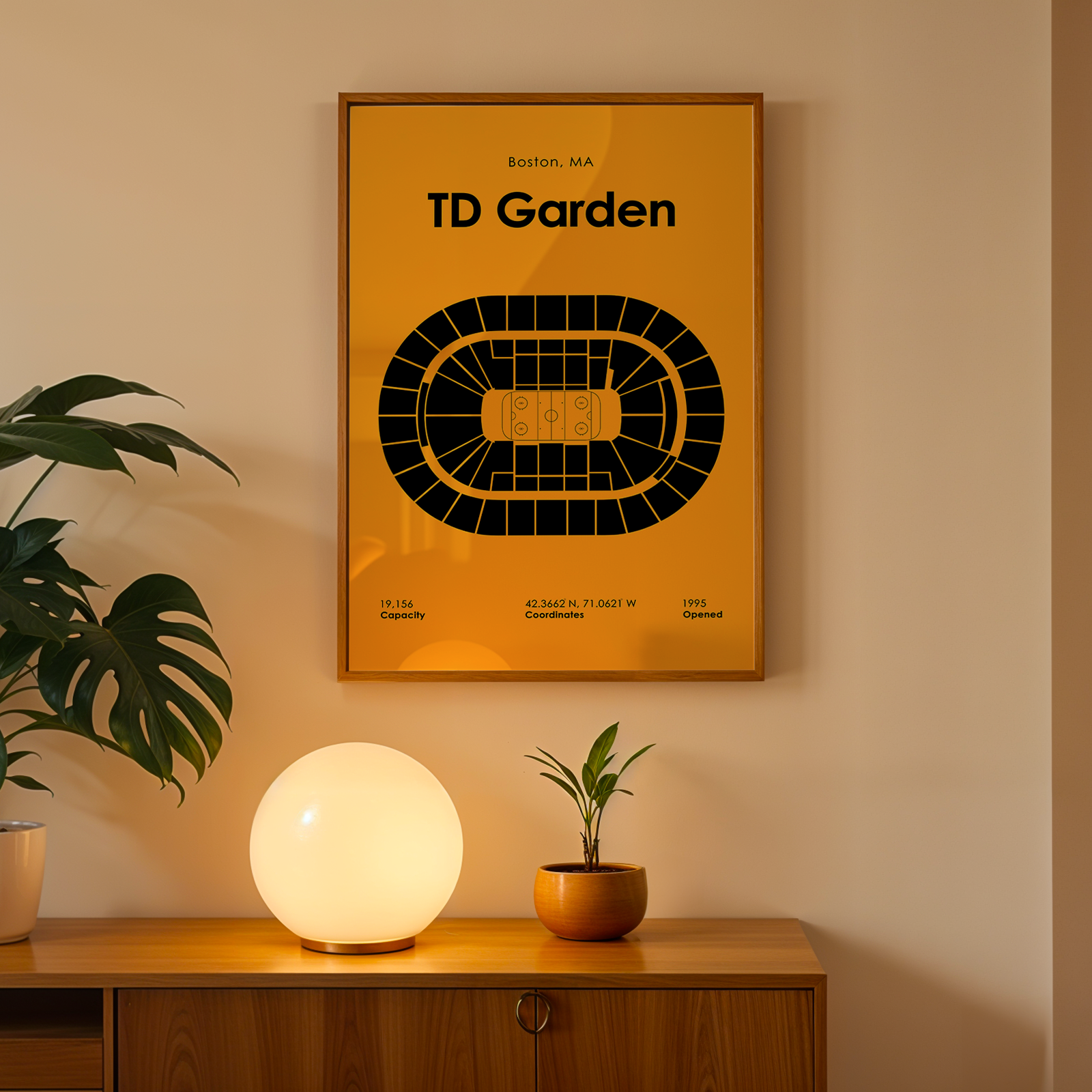 Poster of TD Garden on a wall with a lamp and plant on a wooden surface below.