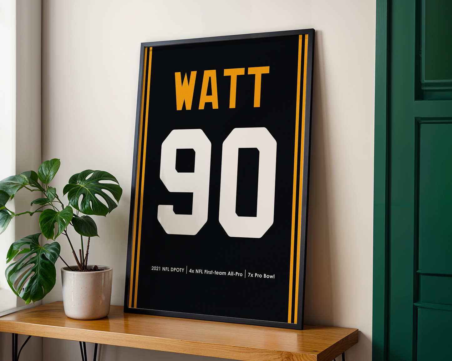 Framed sports jersey with 'WATT' and number '90' on a wooden shelf.