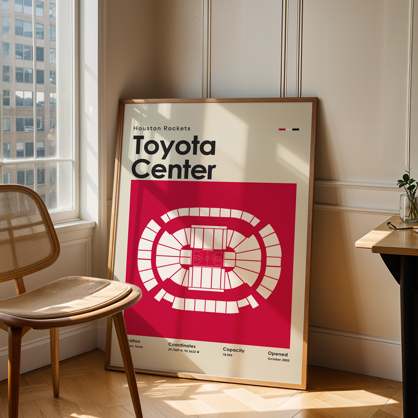 Framed poster of Toyota Center in a room with a chair and table.