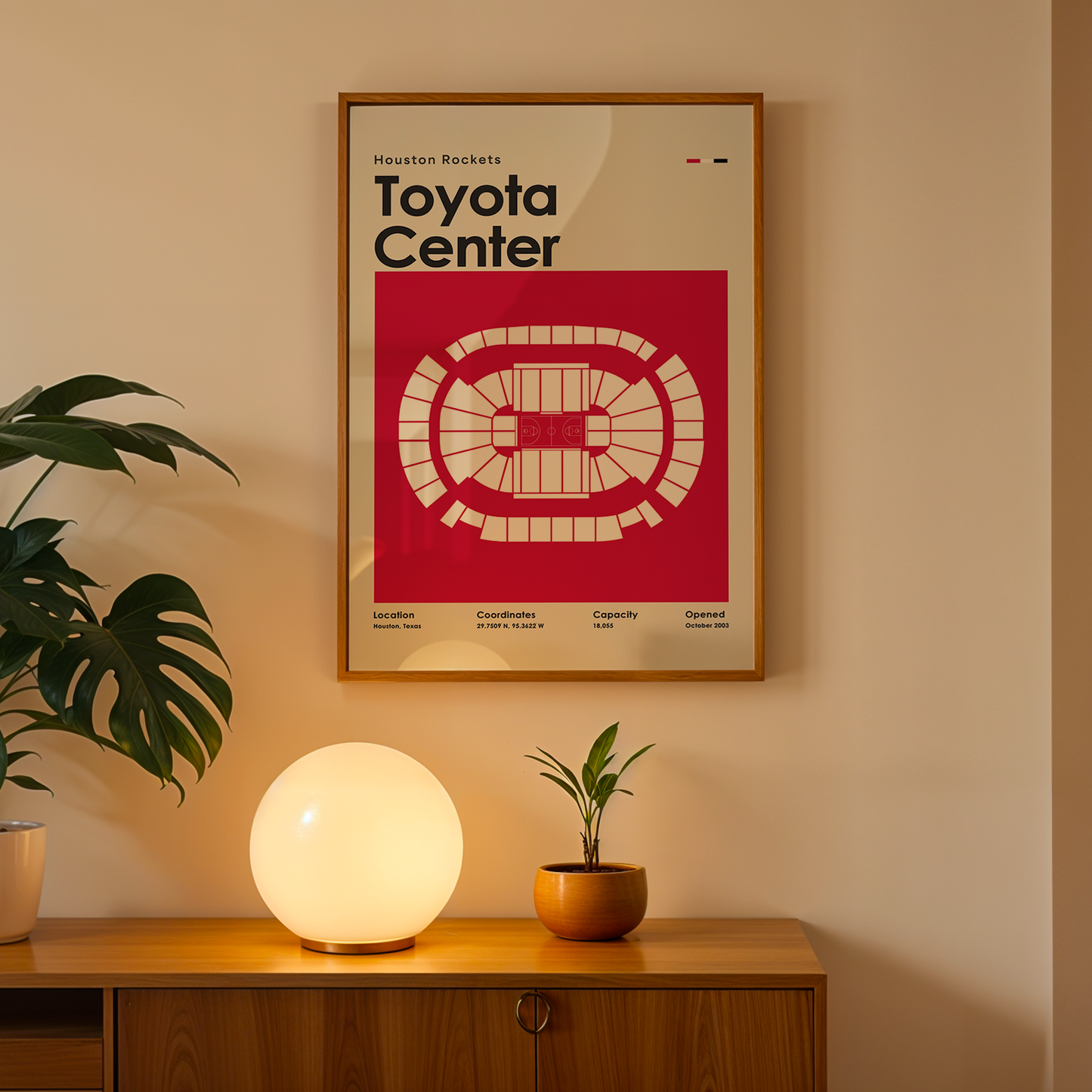 Framed poster of Toyota Center on a wall above a wooden cabinet with decorative items.