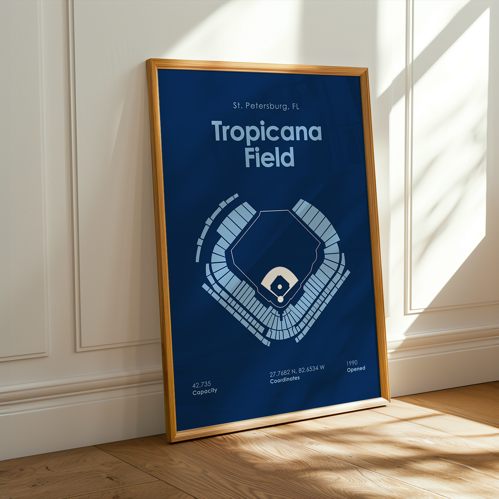 Framed poster of Tropicana Field layout on a wall with sunlight casting shadows.