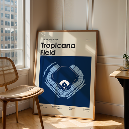 Framed poster of Tropicana Field in a room with a chair and table.