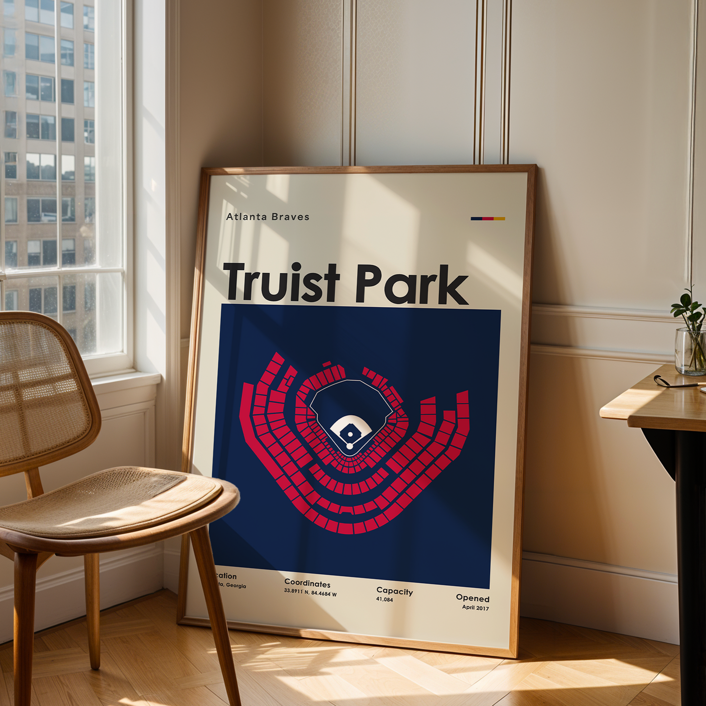 Framed poster of Truist Park in a room with a chair and table.