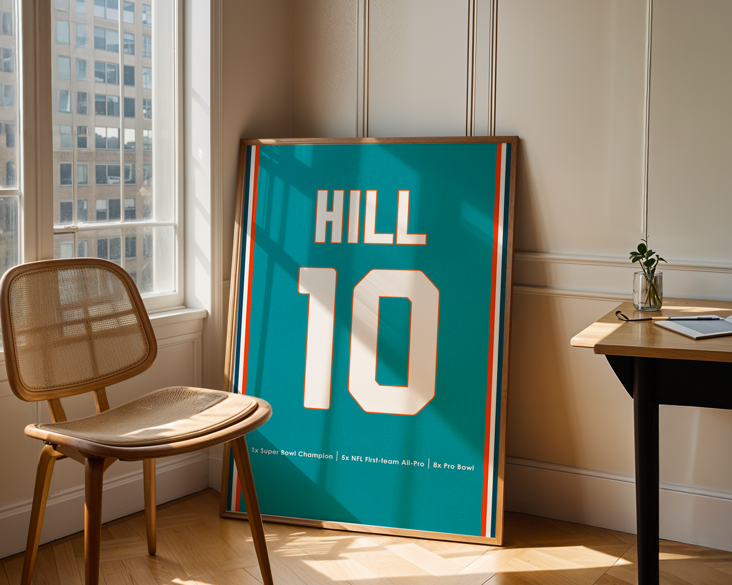 Framed sports jersey with 'HILL 10' on a table in a room with a window.
