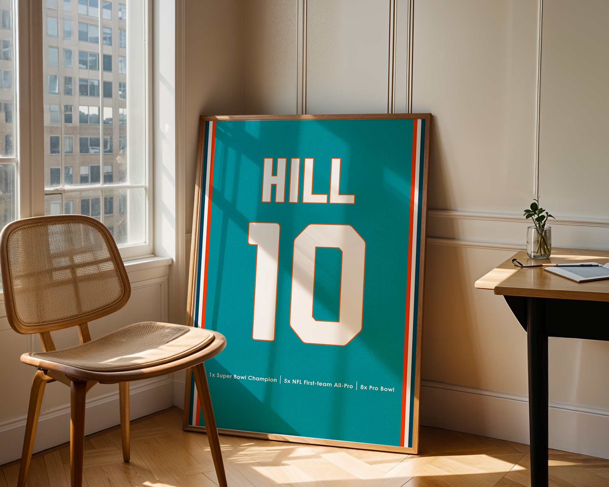 Framed sports jersey with 'HILL 10' on a table in a room with a window.