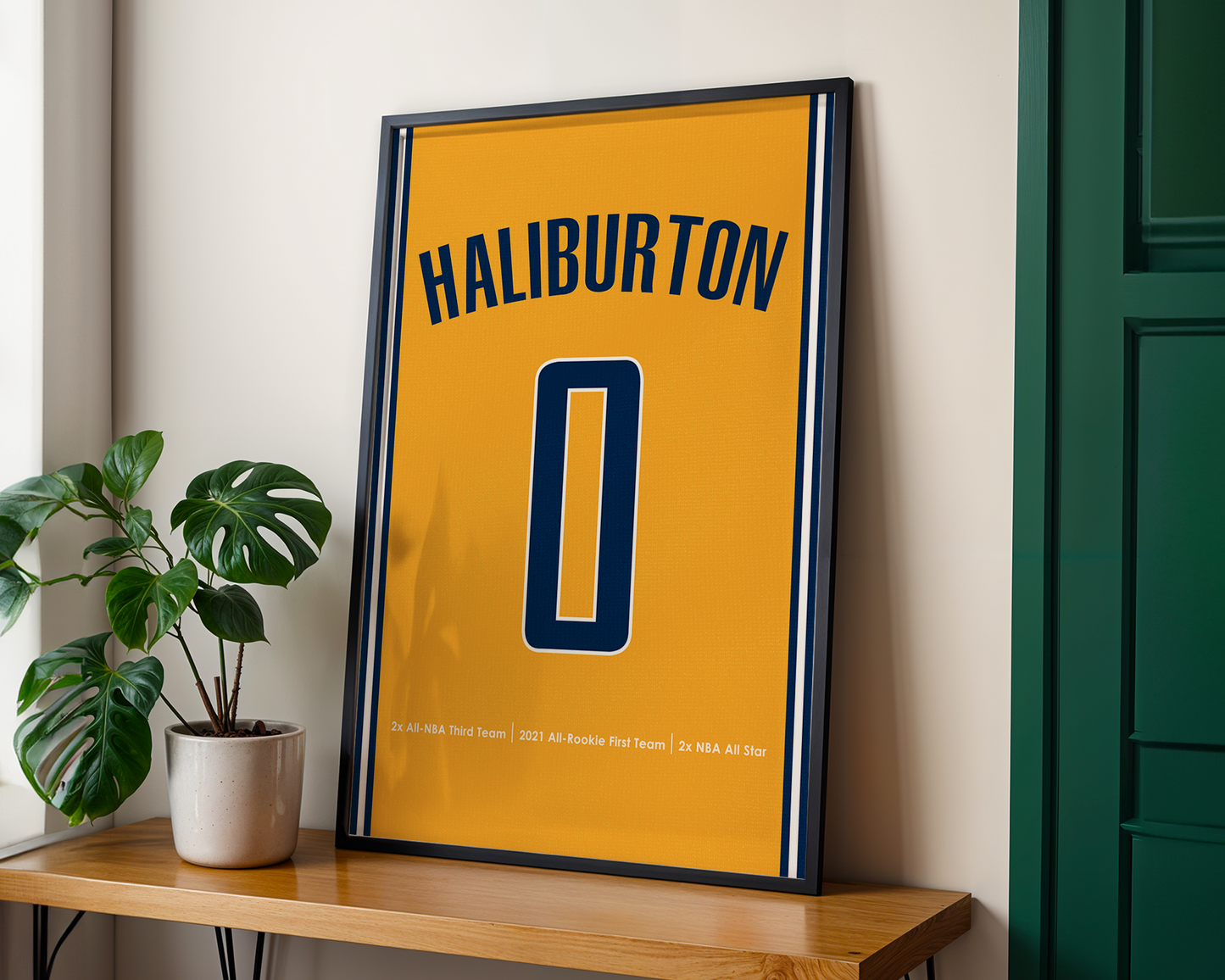 Framed poster with 'Haliburton' and number '0' on a yellow background, placed on a wooden shelf.