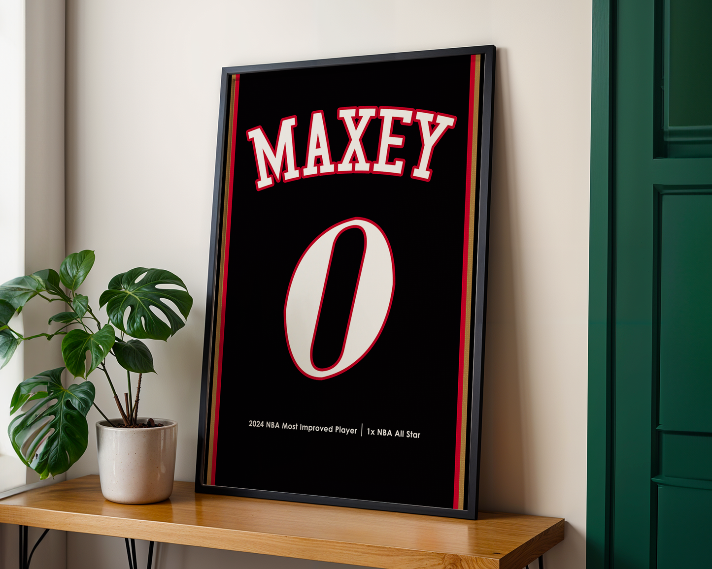 Framed poster with 'MAXEY' and number '0' on a wall next to a plant and wooden shelf.