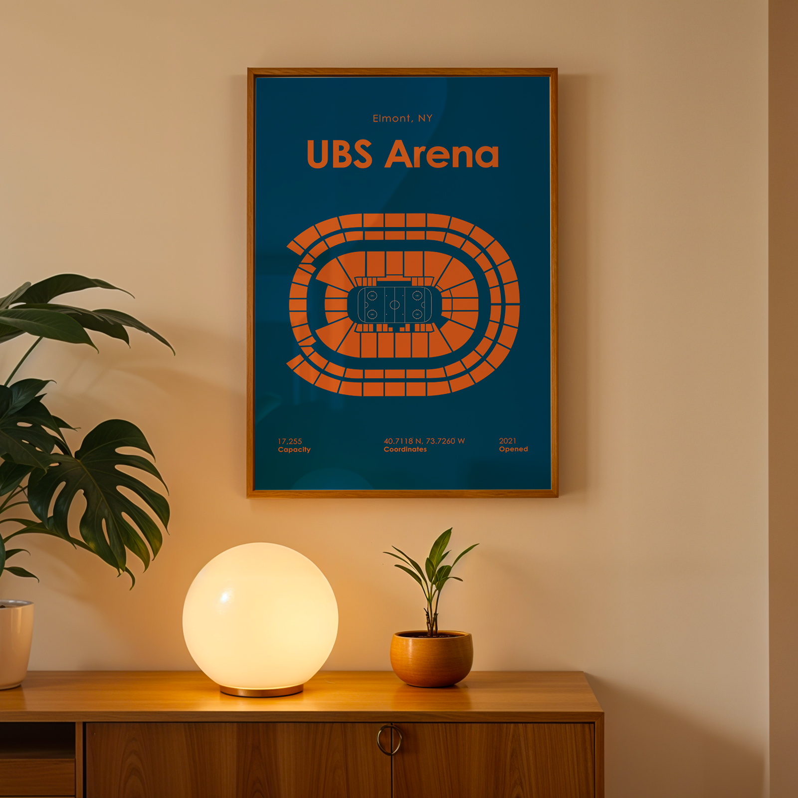 Framed poster of UBS Arena on a wall above a wooden cabinet with decorative items.