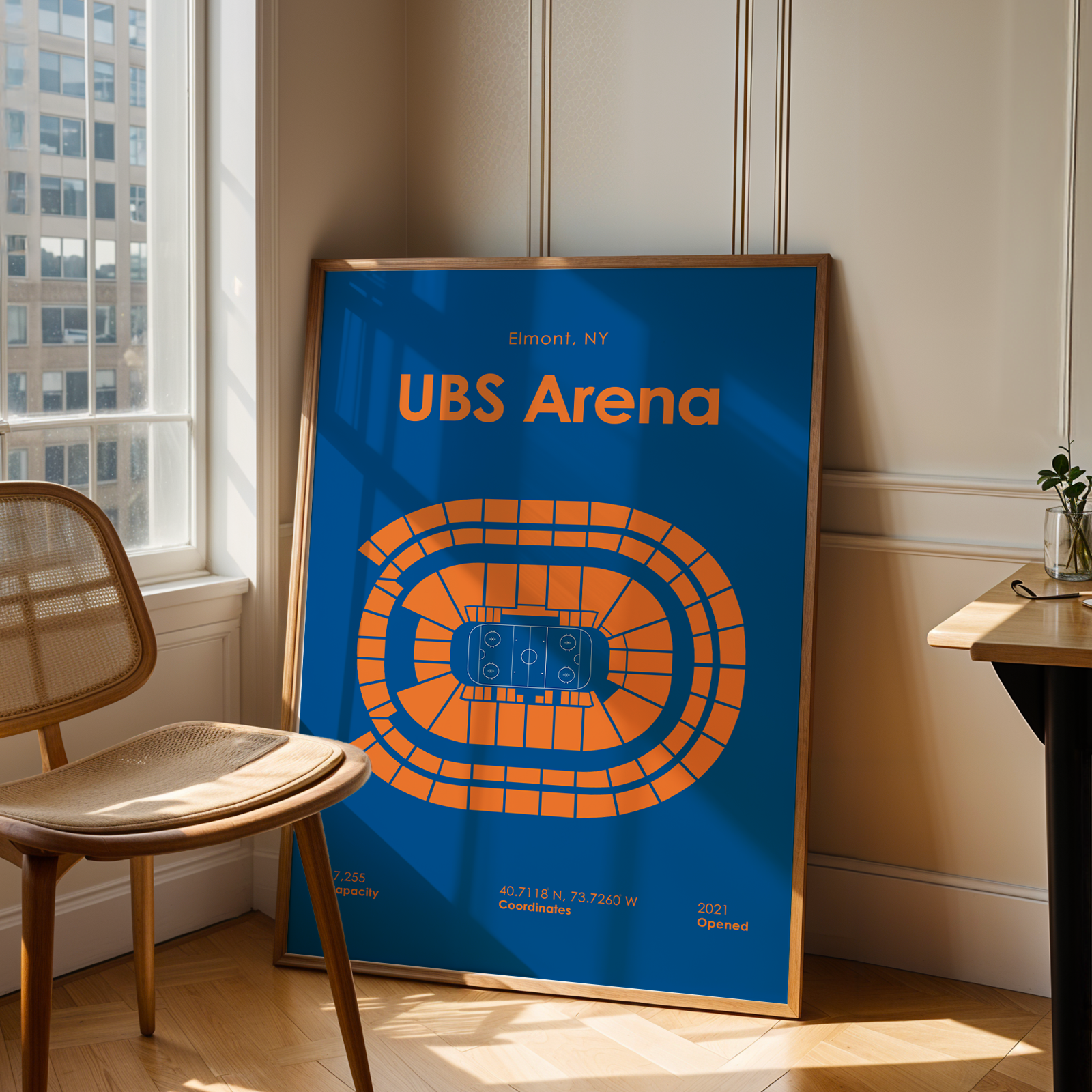 Framed poster of UBS Arena in a room with a window and chair.