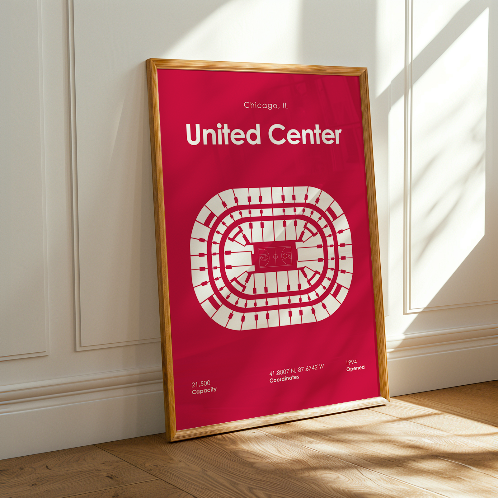 Framed poster of the United Center layout on a red background, leaning against a white wall.