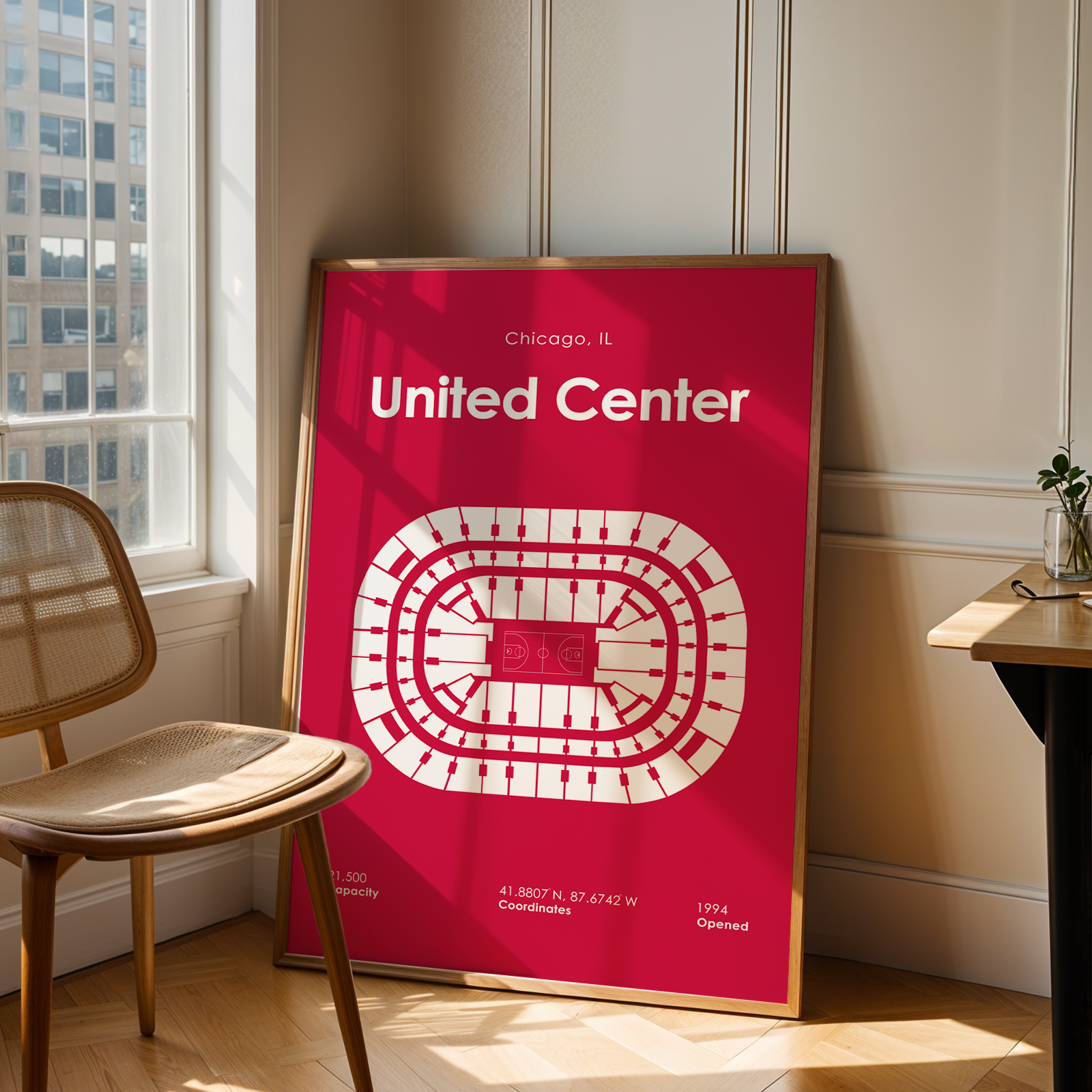 Poster of the United Center in Chicago on a wall next to a chair and table.