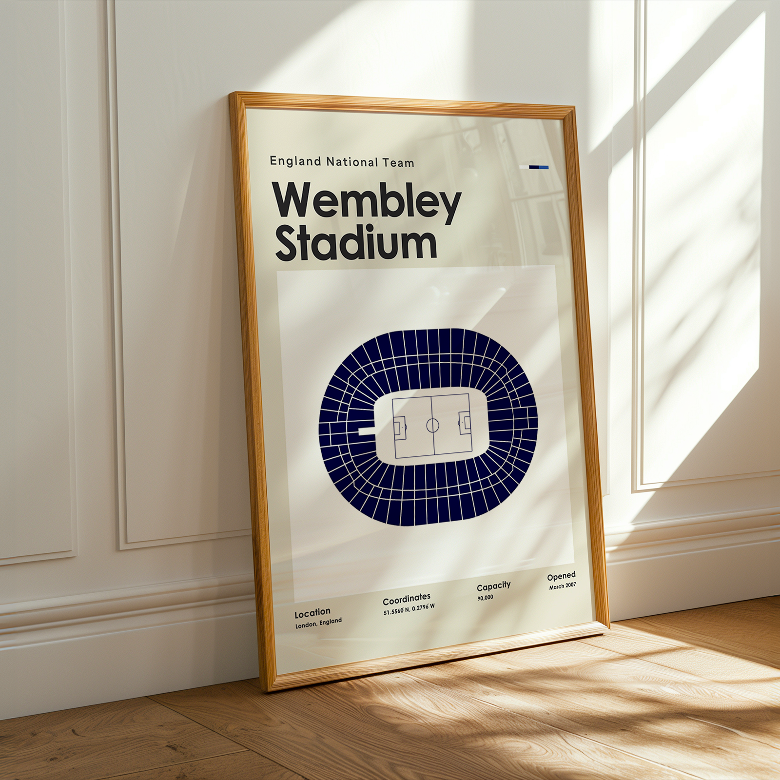 Framed poster of Wembley Stadium on a wall with sunlight casting shadows.