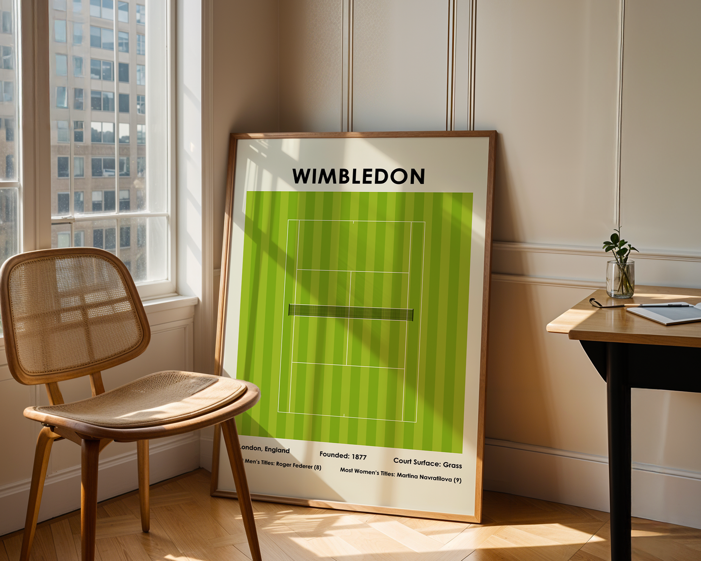 Framed Wimbledon poster on a wall next to a window with a chair and table.
