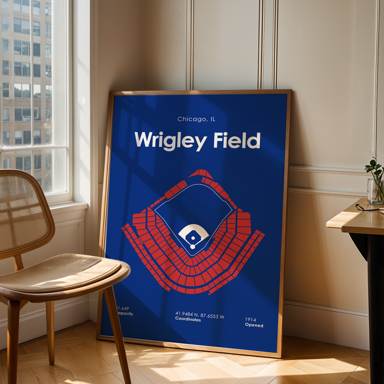 Framed poster of Wrigley Field in a room with a window and chair.