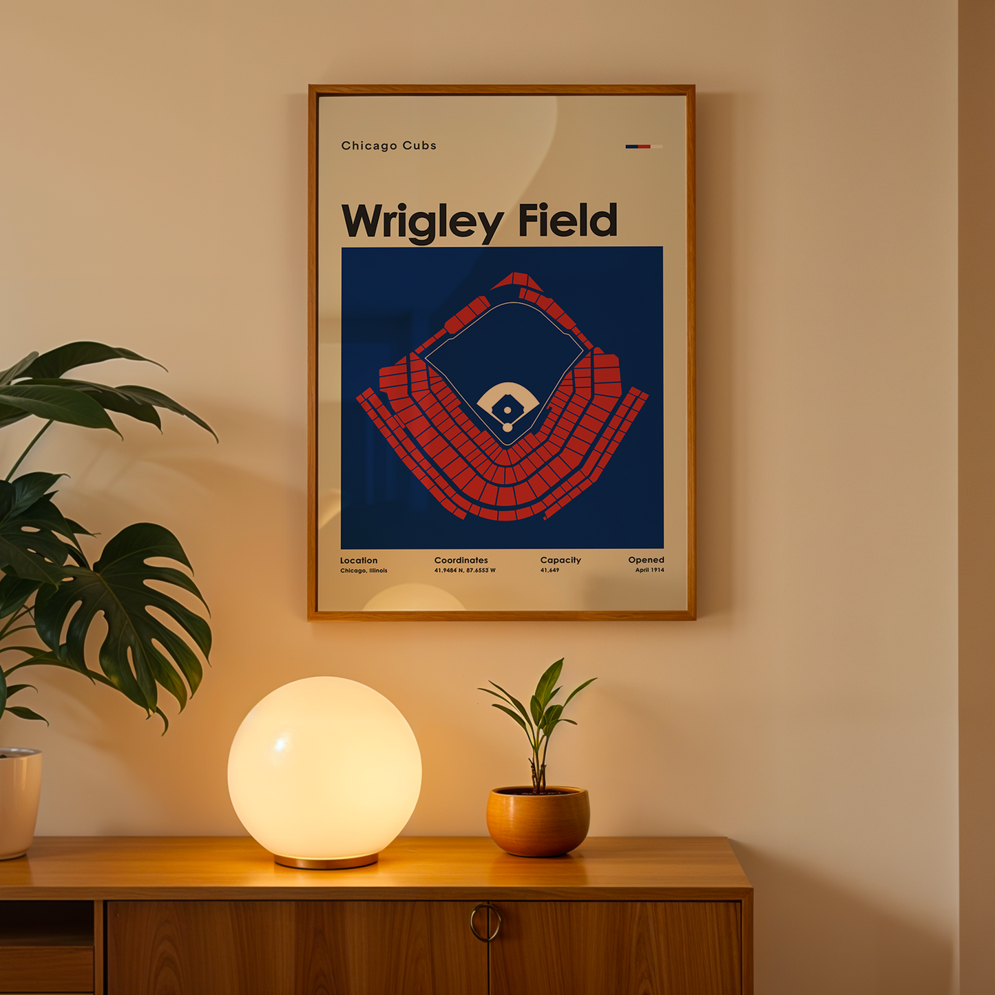 Framed poster of Wrigley Field on a wall above a wooden cabinet with decorative items.