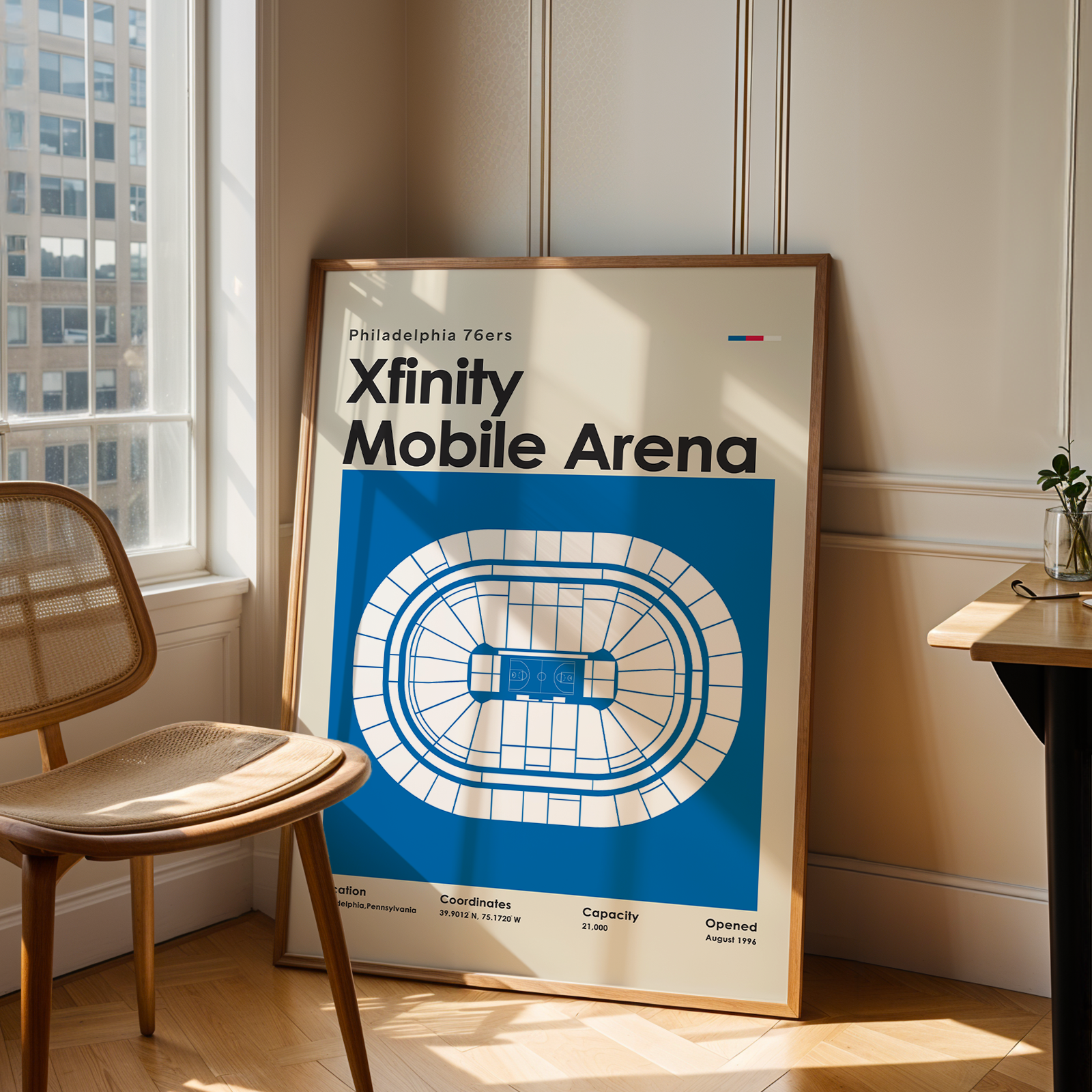 Framed poster of Xfinity Mobile Arena in a room with a chair and window.