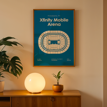Framed poster of Xfinity Mobile Arena on a wall above a wooden cabinet with decorative items.