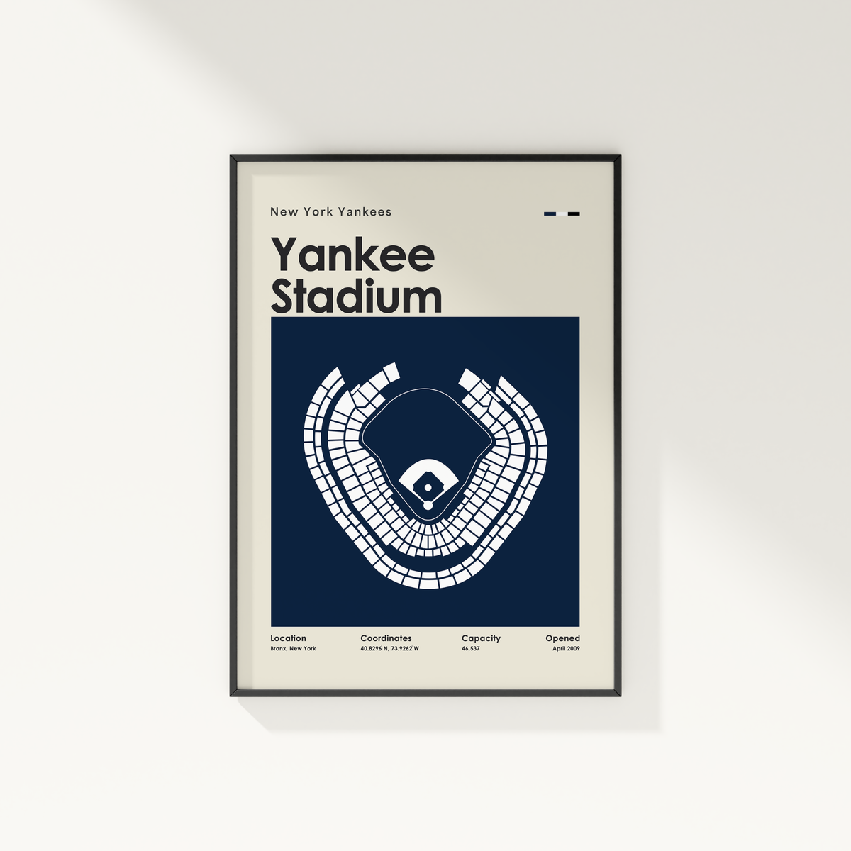 A framed New York Yankees Yankee Stadium poster hanging on a light gray wall. The poster has a cream background with a large navy blue central panel containing a white stadium seating diagram and the text 'New York Yankees' and 'Yankee Stadium'.